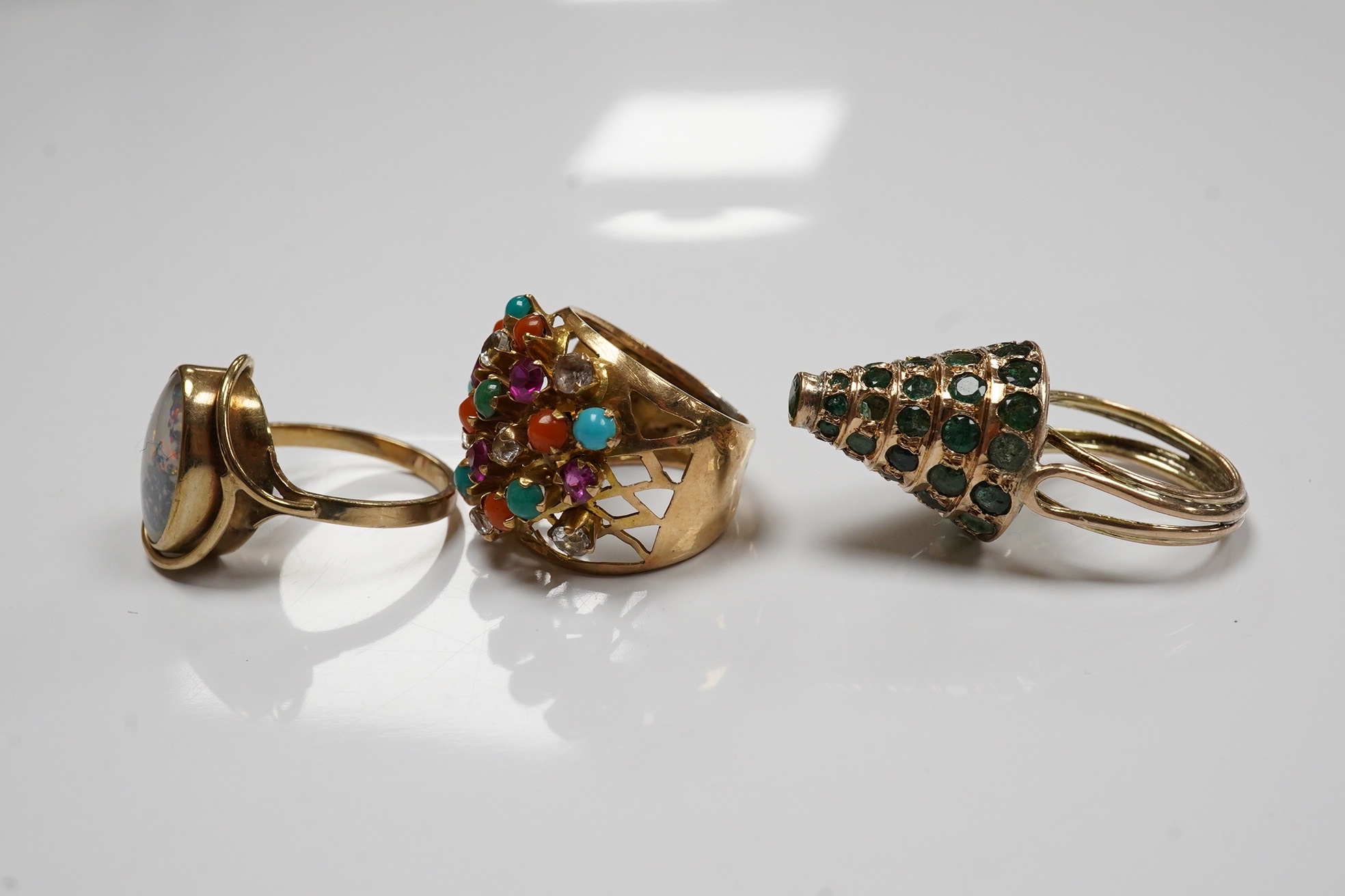 Two Indian? yellow metal and gem set rings including emerald set conical shaped and one other yellow metal and simulated opal set ring. Condition - poor to fair